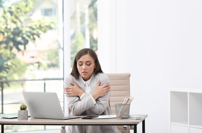 Young woman feeling cold in office