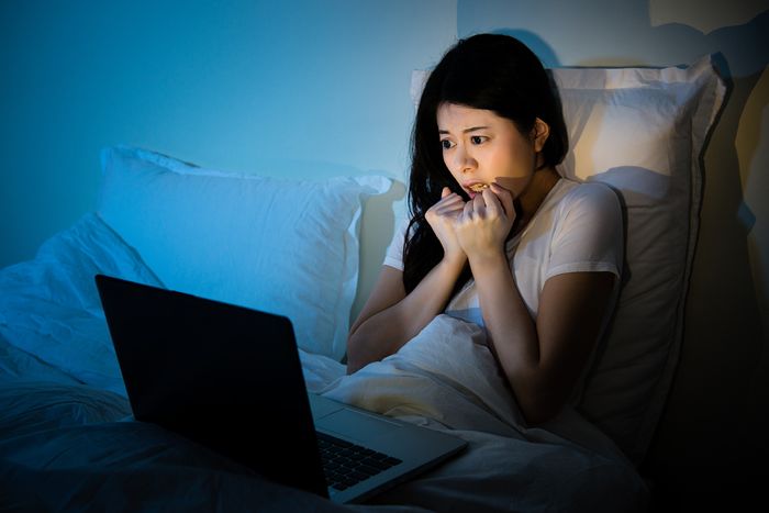 Young woman watching something scary on her laptop