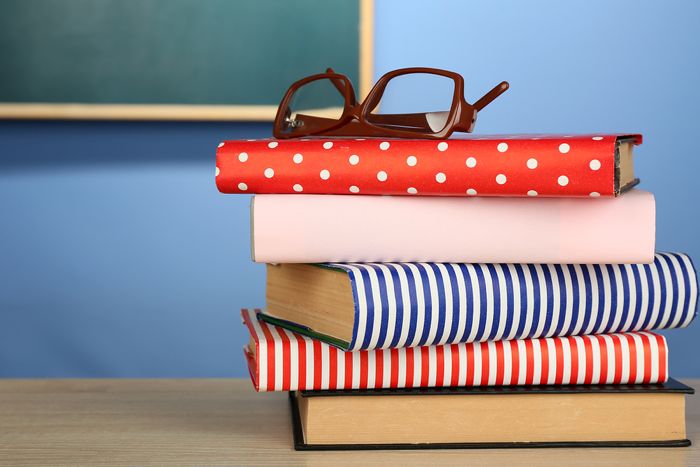 Stack of books with glasses on wooden desk